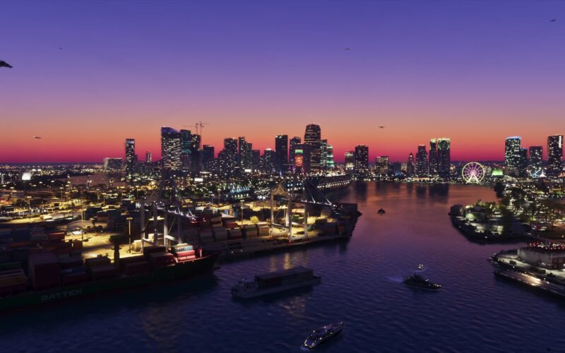 Official Grand Theft Auto VI screenshot of a harbor and city skyline at dusk, with cargo ships and cranes in the foreground and a helicopter in the sky