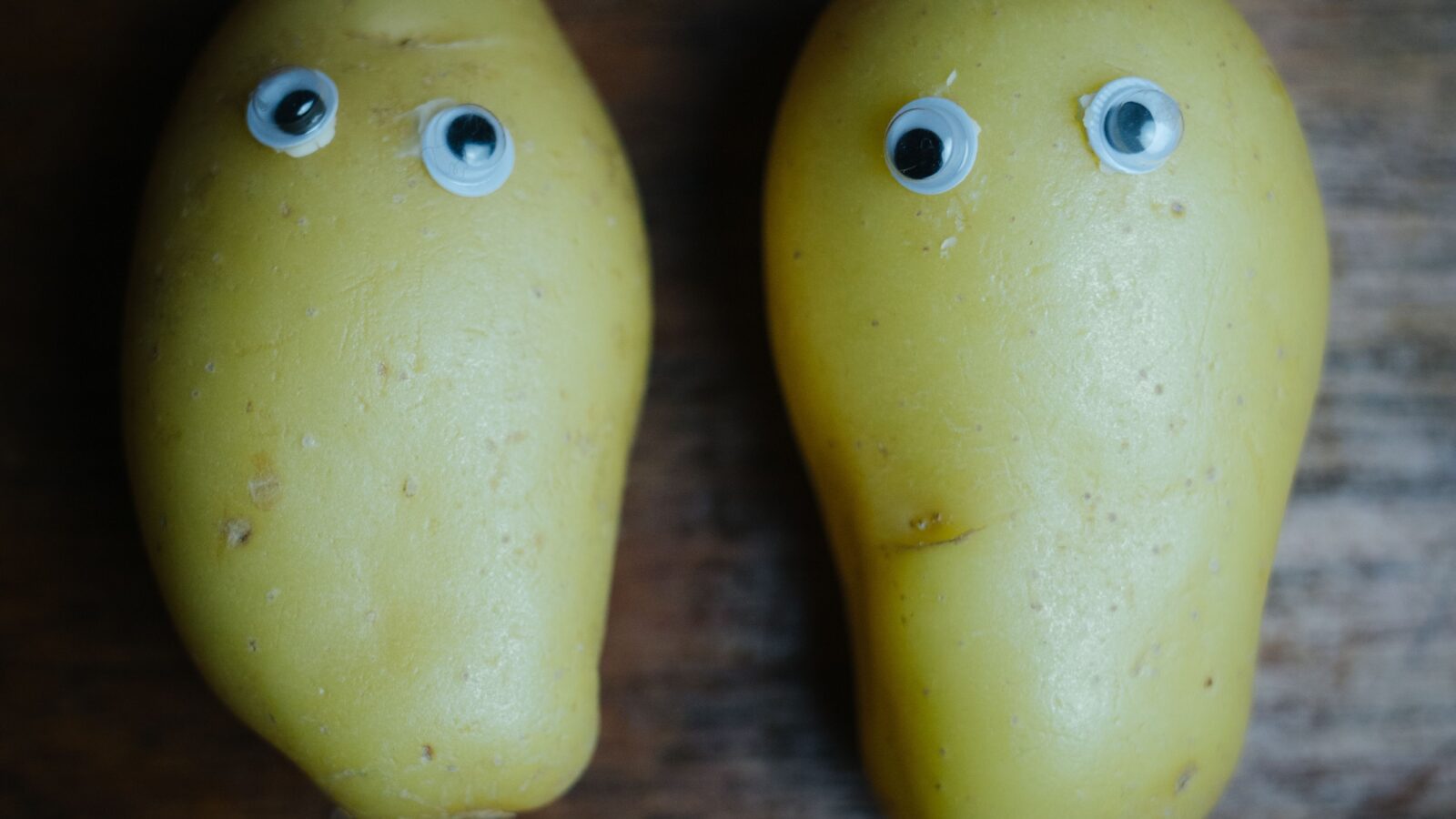 Two potatoes with googly eyes placed on a wooden table, a playful nod to the internet's joke about GTA 6 running on a potato