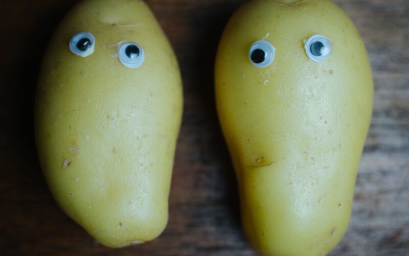 Two potatoes with googly eyes placed on a wooden table, a playful nod to the internet's joke about GTA 6 running on a potato